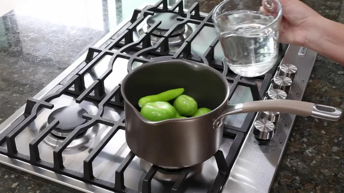 En otra olla, cocinar 1/2 kilo de tomatillos, 2 chiles serranos y agua suficiente por 10 minutos hasta que cambien de color. Retirar del fuego y dejar enfriar.