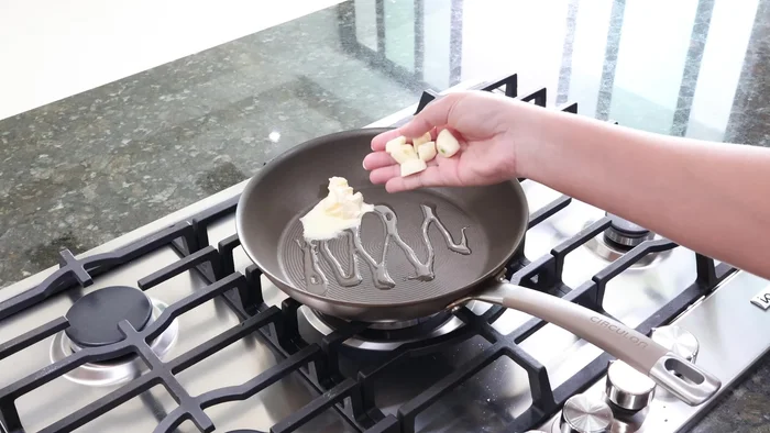 En una sartén, agregar aceite y 1 cucharadita de mantequilla. Agregar 4 dientes de ajo y sofreír hasta que suelten su sabor.