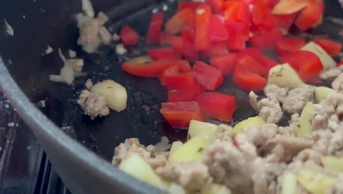 Agregar el pimiento rojo y las papas fritas a la mezcla. Cocinar hasta que los pimientos estén tiernos.