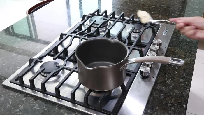 Reserva la salsa. En una olla, derrite mantequilla, agrega cebolla finamente picada y un diente de ajo. Mezcla.
