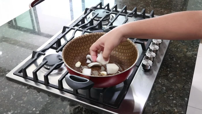 Agrega dos jitomates picados, canela, clavos de olor y orégano seco. Incorpora 10 pimientas chicas y mezcla bien. Agrega una taza de agua, tapa y cocina por 10 minutos.
