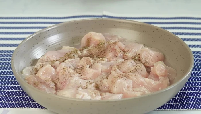 Añadir pimienta negra, páprica y sal al pollo. Mezclar bien. (150.28)
