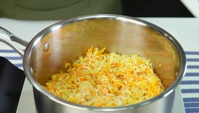 Agregar sal, pimienta y agua caliente (el doble de la cantidad de arroz). Cocinar a fuego bajo hasta que el arroz forme huequitos, luego tapar completamente y dejar reposar 10 minutos. (337.88)