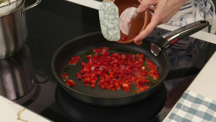 Saltear el pimiento rojo y la cebolla morada a fuego alto hasta que estén ligeramente crujientes. (110.04)