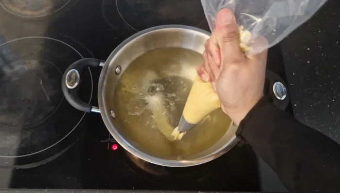 Con la manga pastelera, forma tiras de masa sobre papel de horno (o directamente en el aceite caliente con cuidado). Corta las tiras con unas tijeras; el tamaño depende de tu preferencia.