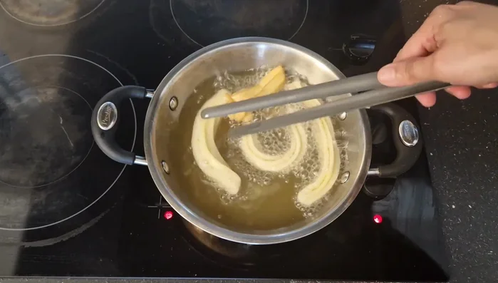 Fríe los churros en el aceite caliente, girándolos hasta que estén dorados (aproximadamente 12-15 minutos). Retira y coloca sobre papel absorbente.