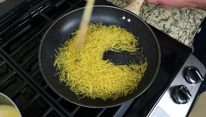 Añadir los fideos a la sartén caliente y freírlos durante 3-4 minutos, removiendo constantemente hasta que estén ligeramente dorados. (157.72)