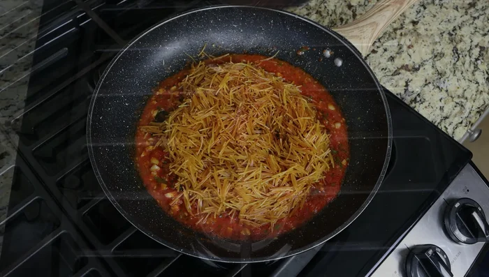 Añadir gradualmente el caldo de pescado hirviendo a los fideos, mezclando hasta que se integren todos los ingredientes. (267.04)