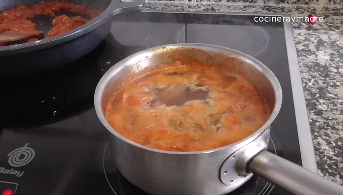 Colar el caldo de las cabezas y pieles de langostinos. Agregar una parte de este caldo a la salsa de tomate.