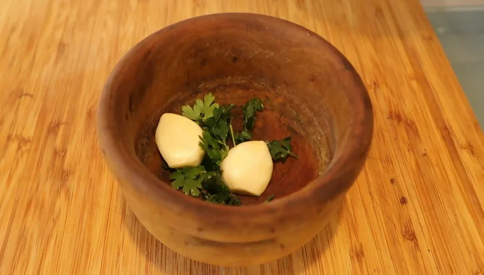 Preparamos el marinado: Machacamos perejil y ajo en un mortero con sal y pimienta. Añadimos aceite de oliva.