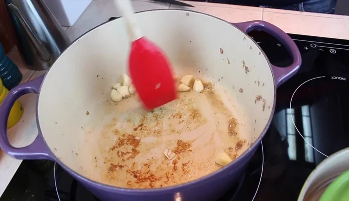 Añadir más aceite a la olla, dorar los ajos brevemente, luego agregar el pimiento verde y la cebolla. Sofreír hasta que estén pochados.