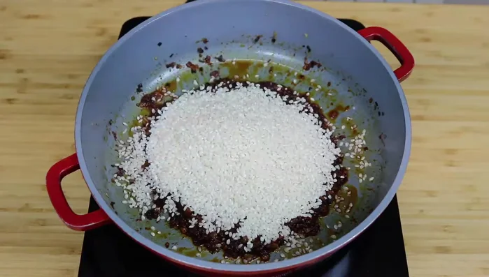Incorpora el arroz al sofrito y mezcla bien. Calienta el fumet de pescado en un cazo.