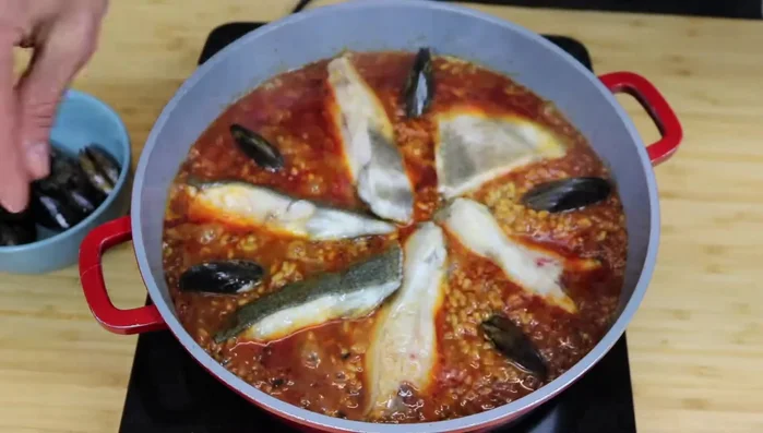 A los 18 minutos, añade los mejillones, hundiendolos ligeramente en el arroz. Deja cocer 3-4 minutos más.