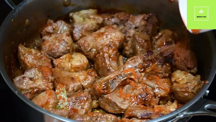Agregar páprika (o achiote o tomate en polvo), mezclar y cocinar hasta que el cerdo esté dorado (449.88 - 534.779).