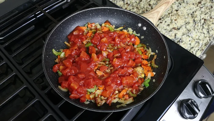 Agregar una lata (425 g) de tomates cortados en cubitos, 360 ml de caldo de pescado (o caldo de verduras, pollo o agua), 0.17 g de hebras de azafrán, sal y pimienta. Llevar a ebullición a fuego alto.
