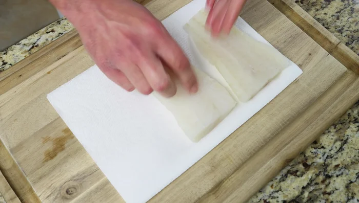Mientras las papas se cocinan, secar completamente tres filetes de bacalao (225 g cada uno) con toallas de papel. Sazonar con sal y pimienta por un lado, cortar cada filete en dos y reservar.
