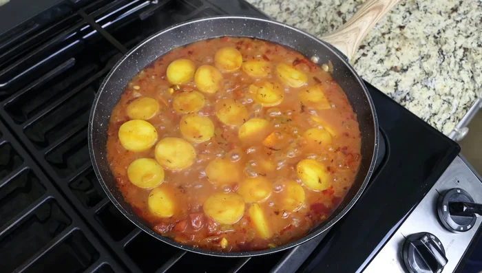 Después de 20 minutos, quitar la tapa de la sartén. Agregar los trozos de bacalao a la sartén en una sola capa, espaciados uniformemente. Tapar y cocinar a fuego lento durante 5 minutos, o hasta que el pescado esté cocido.