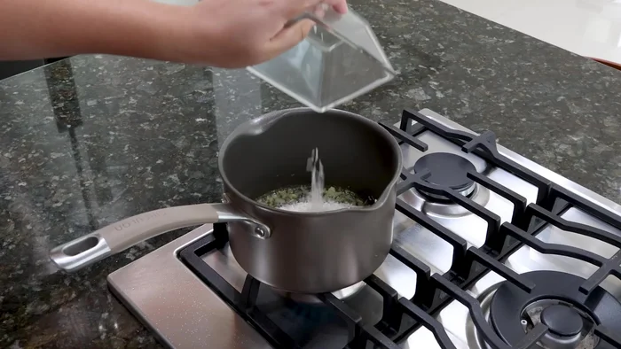 Agregar 1 taza de arroz limpio, sazonar con consomé de pollo y mezclar hasta que esté sofrito.