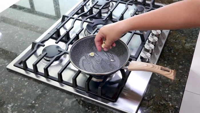 En otra sartén, sofreír 2 dientes de ajo, cebolla, y chile verde.