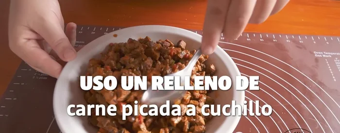 Rellenar y cerrar las empanadas: Colocar una porción de relleno en el centro de cada tapa, humedecer los bordes para sellar y cerrar.