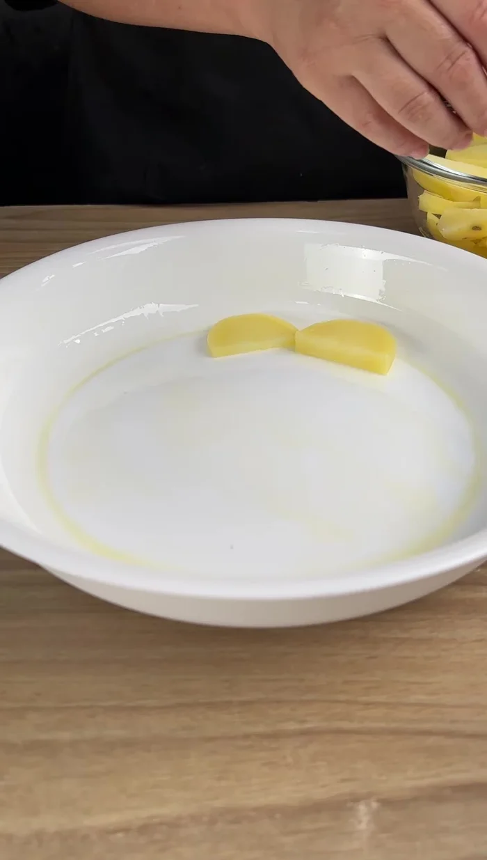 Colocar las papas en una bandeja engrasada con aceite de oliva, formando una base uniforme.