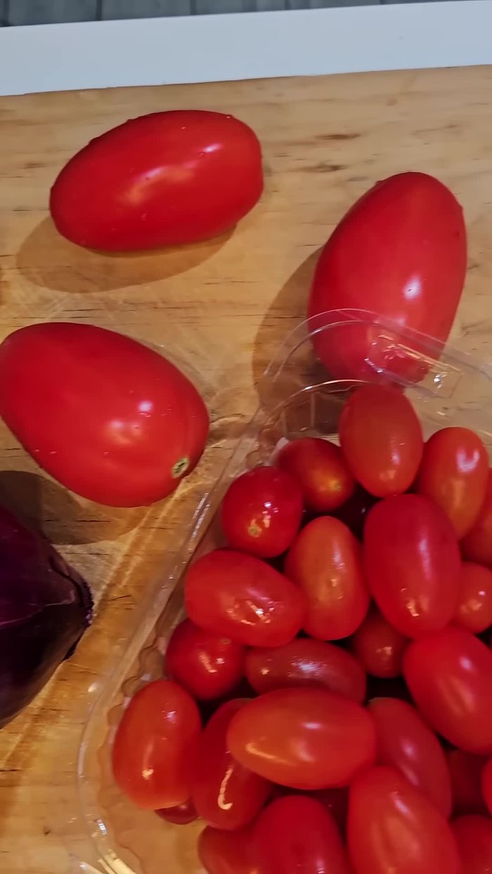 Precalentar el horno a 200ºC. Colocar los tomates cherry, cebolla morada, ajo y chile pimiento en una bandeja para hornear. Agregar aceite de oliva, sal, pimienta y orégano.