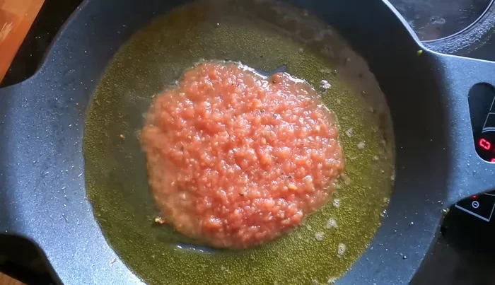 Hacer el sofrito en la paella: añadir un poco de aceite, tomate rallado, cebolla, y cocinar hasta que el tomate reduzca y la cebolla esté transparente.