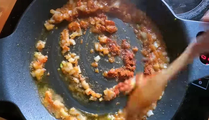 Incorporar pimentón mezclado con ñora, ajo picado y perejil. Cocinar hasta que reduzca.