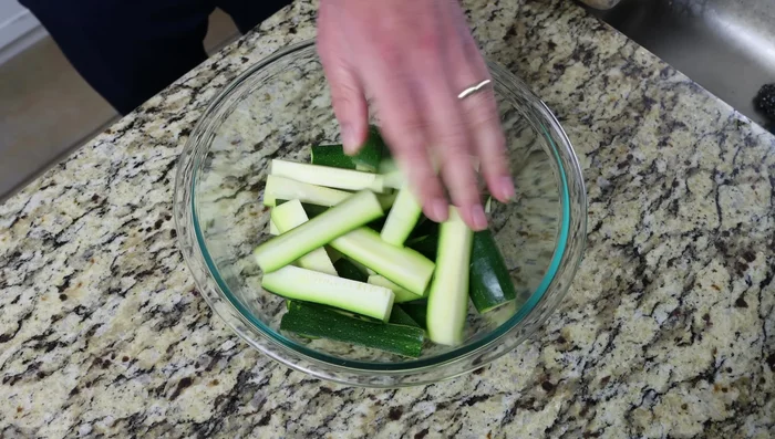 Añadir los palitos de calabacín a un tazón grande, sazonar generosamente con sal marina y mezclar bien. Dejar reposar durante 10 minutos para que la sal extraiga el agua.