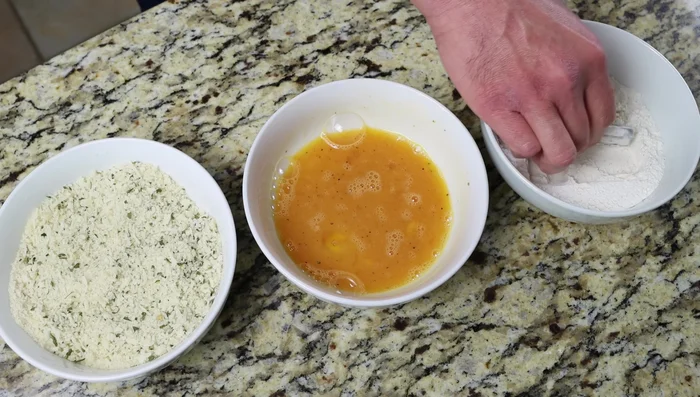 Rebozar los palitos de calabacín: primero en la harina, luego en el huevo batido y finalmente en el pan rallado. Asegurarse de que estén completamente cubiertos.
