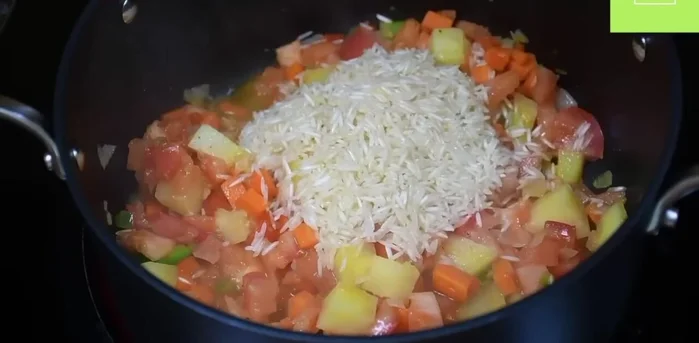 Agregar arroz, consomé de pollo y agua. Mezclar y dejar cocinar hasta que el arroz esté cocido y las verduras estén suaves. (317.6)