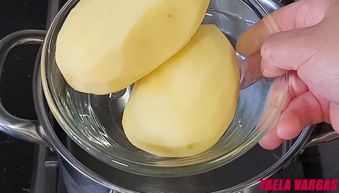 Cocer las patatas: En una cazuela con agua a fuego máximo, cocinar las patatas hasta que rompa a hervir. Bajar el fuego a medio y cocinar entre 20 a 30 minutos, dependiendo del tamaño. Sacar las patatas y aplastarlas inmediatamente con un tenedor, dejando algunos trozos.