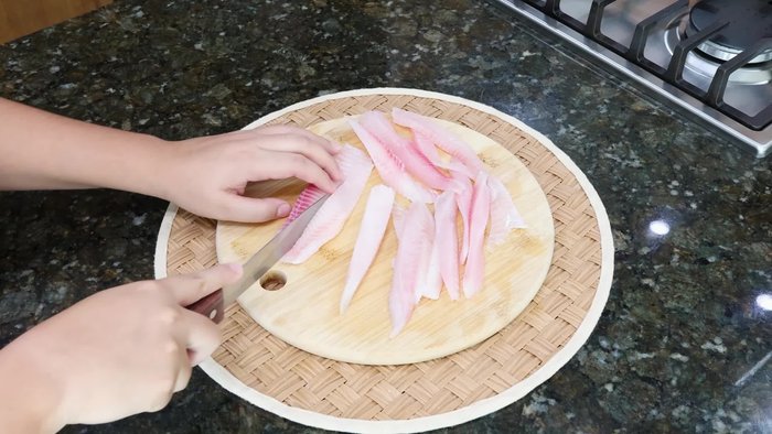 Cortar los filetes de pescado en tiras y sazonar con sal, pimienta negra y ajo en polvo.