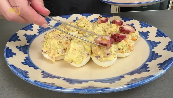 Decorar cada mitad de huevo con una rodaja de pulpo y espolvorear con pimentón ahumado picante.