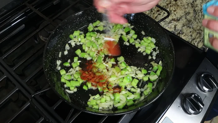 Añadir el pimentón dulce ahumado, mezclar rápidamente y añadir el tomate rallado. Cocer a fuego lento durante unos 5 minutos.