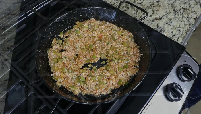 Agregar lentamente el caldo de verduras hirviendo, mezclando cada 3 minutos aproximadamente para liberar el almidón del arroz.