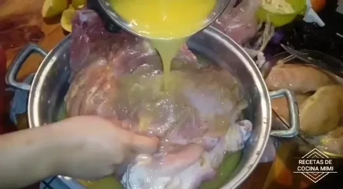 Agregar el jugo de naranja a la pierna de cerdo, volteándola para que se impregne por todos lados.