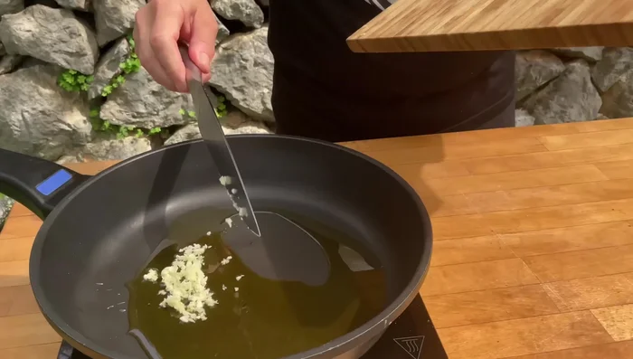 Sofreír el ajo y la guindilla: En una sartén, sofreír el ajo picado y la guindilla en aceite de oliva (275.96).