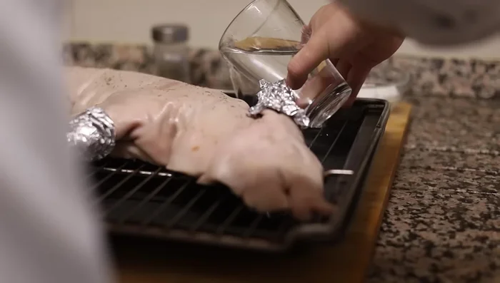 Verter dos vasos de agua en la bandeja, sin que el agua toque el cochinillo.