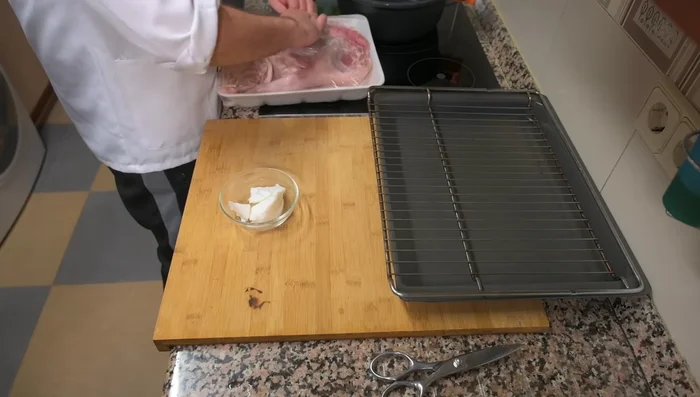 Colocar el cochinillo en una bandeja con una rejilla encima. Esto permite que el agua que añadiremos luego le dé humedad sin que esté en contacto directo con la bandeja.