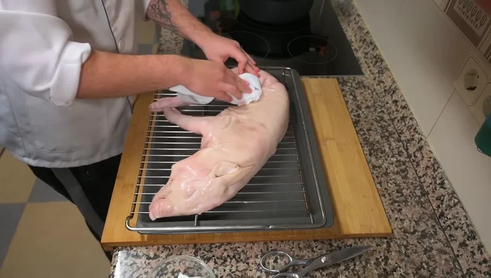 Limpiar la piel del cochinillo con papel de cocina para eliminar impurezas. Si hay alguna parte quemada, se puede retirar con un soplete o unas pinzas.