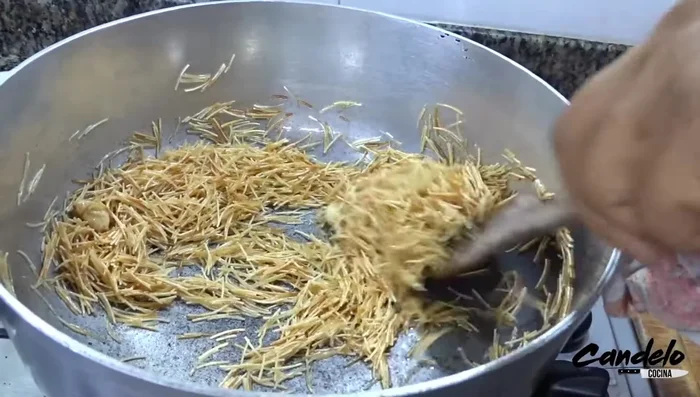 Preparar el arroz de fideos: sofreír ajo, agregar fideos y tostar. Agregar arroz, agua, sal y aceite. Cocinar a fuego lento por 20 minutos mínimo.