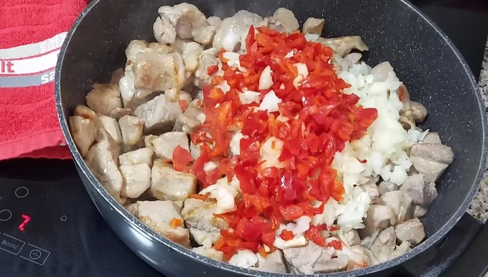 Bajar el fuego a medio. Agregar el laurel y sofreír la cebolla y el pimiento hasta que estén tiernos.