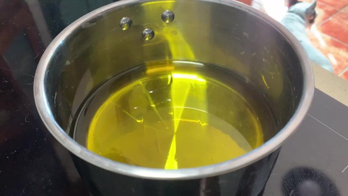 Machacar ligeramente dos dientes de ajo con la parte plana de un cuchillo. Agregar una rama de romero al aceite de oliva.
