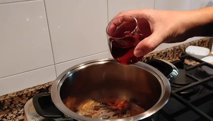Preparar el caldo de mariscos: en una olla, sofreír las carcasas de langostinos con la mitad del coñac. Añadir agua (aprox. 2 litros), la otra media cebolla y el perejil. (200.56)