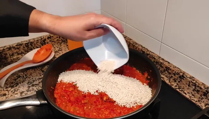 Incorporar el arroz al sofrito, rehogar y añadir el caldo de mariscos (aprox. 1 litro). (559.839)