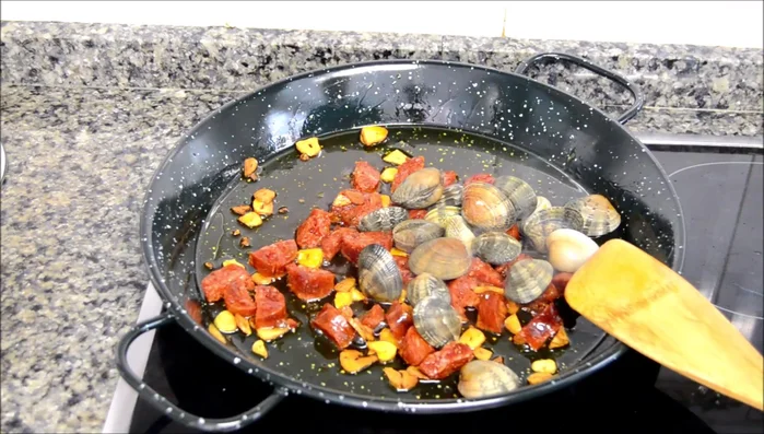 Añadir las almejas, mezclar con el chorizo y los ajos.