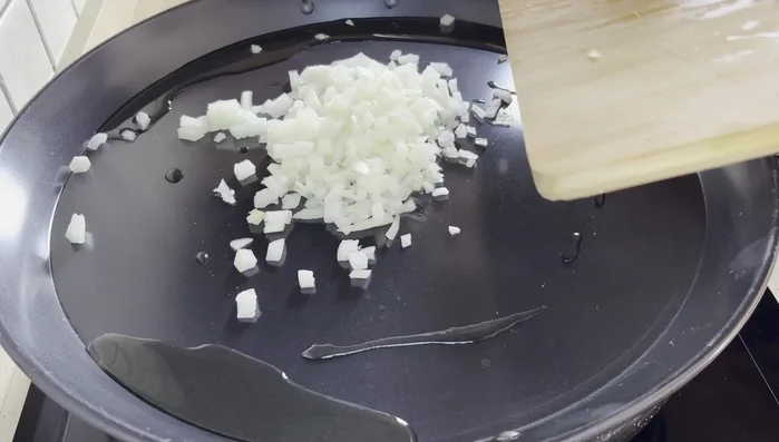 En una paella, calentar aceite de oliva. Agregar la cebolla, sal marina gruesa y sofreír hasta que esté blandita y transparente. (Fuego medio)