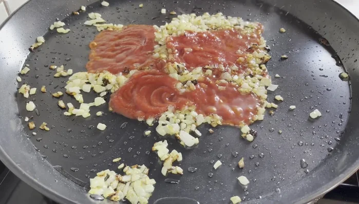 Incorporar el tomate triturado, rectificar de sal y mezclar hasta que suelte el agua y espese.