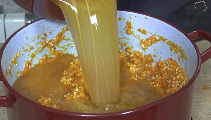 Incorporar el arroz a las verduras y agregar el caldo caliente. Remover.